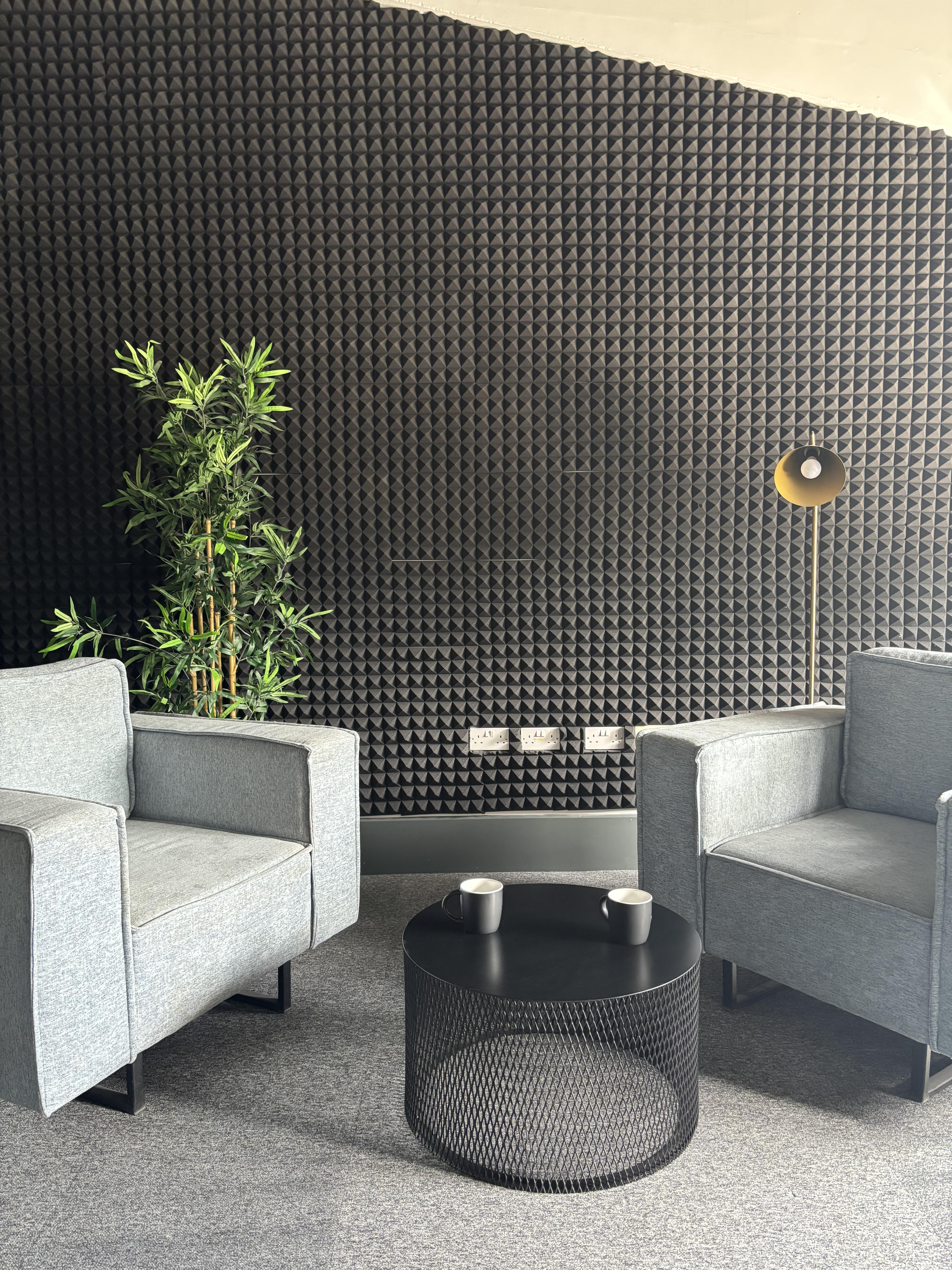 Two grey armchairs facing a coffee table in Sandiford Studios' communal networking lounge